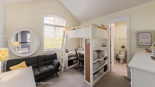bedroom with an office area, vaulted ceiling, light colored carpet, and ensuite bathroom