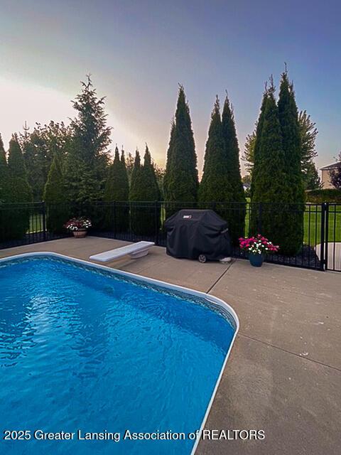 pool at dusk featuring a patio and fence