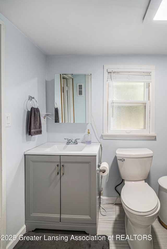 15496 Park Lake Rd, East Lansing, MI 48823 - half bathroom featuring baseboards, toilet, and vanity