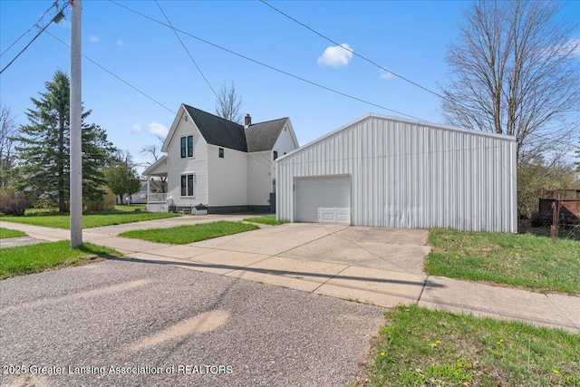 607 Ogemaw St, Grayling, MI 49738 - view of property exterior with driveway, an outdoor structure, a garage, and a lawn