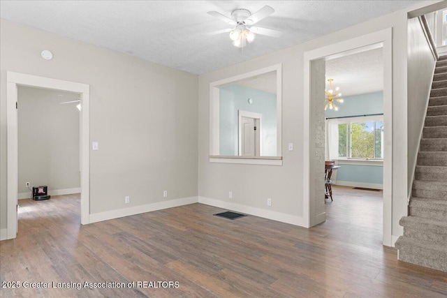 607 Ogemaw St, Grayling, MI 49738 - spare room featuring stairs, ceiling fan, wood finished floors, baseboards, and a chandelier