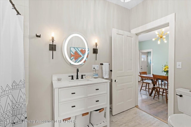 607 Ogemaw St, Grayling, MI 49738 - bathroom with wood finished floors, vanity, toilet, and a chandelier