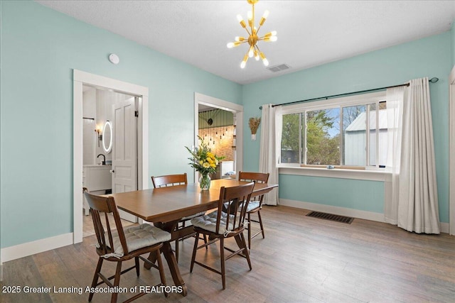 607 Ogemaw St, Grayling, MI 49738 - dining room with a chandelier, wood finished floors, and baseboards