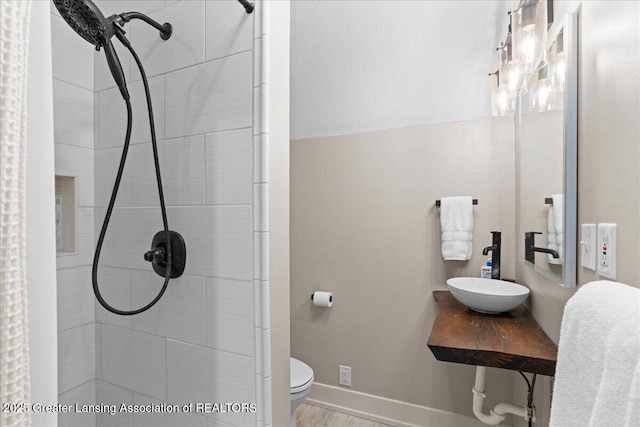607 Ogemaw St, Grayling, MI 49738 - full bath featuring a sink, a tile shower, toilet, and baseboards