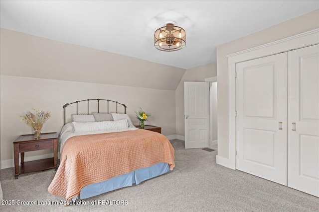 607 Ogemaw St, Grayling, MI 49738 - bedroom with light carpet, vaulted ceiling, baseboards, and a closet