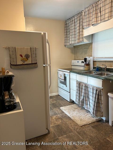 1209 Hapeman St, Lansing, MI 48915 - kitchen featuring white appliances, a sink, dark countertops, and dark stone finish floors