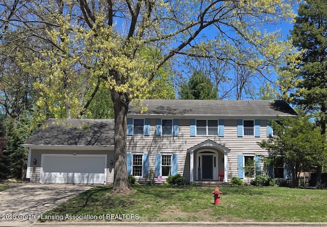 colonial house with a garage, driveway, and a front lawn