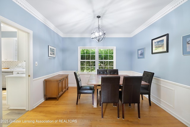 2038 Woodfield Rd, Okemos, MI 48864 - dining space featuring a chandelier, light wood-style flooring, wainscoting, and crown molding