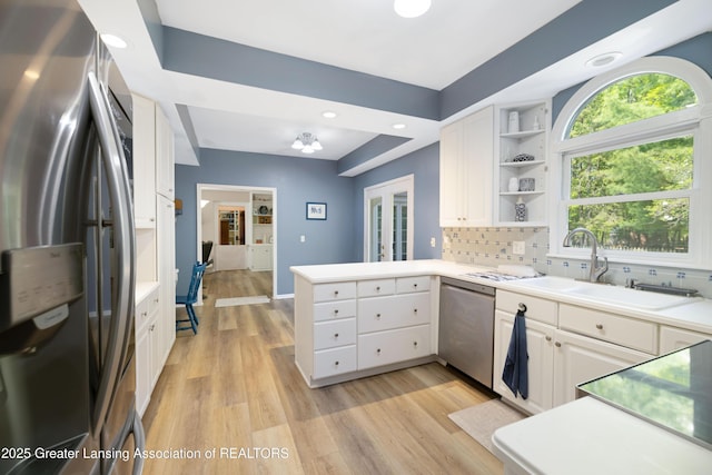 2038 Woodfield Rd, Okemos, MI 48864 - kitchen featuring appliances with stainless steel finishes, a peninsula, open shelves, a sink, and white cabinetry