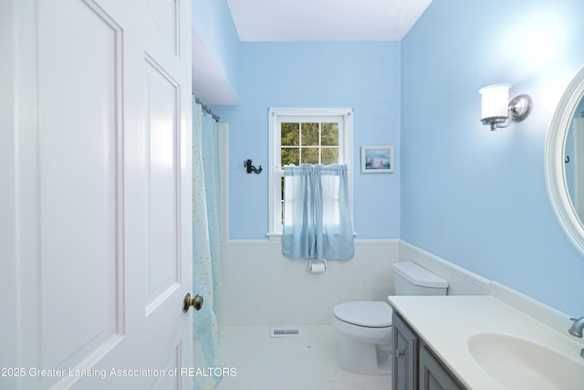 2038 Woodfield Rd, Okemos, MI 48864 - bathroom featuring a wainscoted wall, tile patterned flooring, tile walls, toilet, and vanity