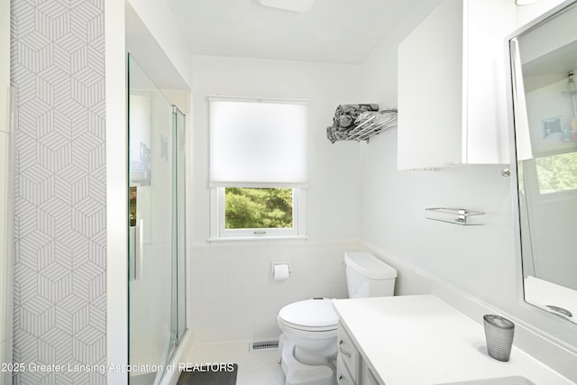 2038 Woodfield Rd, Okemos, MI 48864 - full bathroom with tile walls, healthy amount of natural light, a stall shower, vanity, and toilet