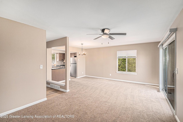 1626 Pepper Tree Ln Unit 13, Lansing, MI 48912 - unfurnished living room featuring light colored carpet, a ceiling fan, a chandelier, and baseboards