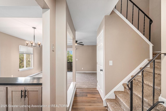 1626 Pepper Tree Ln Unit 13, Lansing, MI 48912 - stairs featuring a chandelier, wood finished floors, a ceiling fan, and baseboards