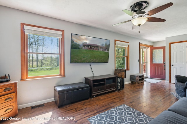 living area with healthy amount of natural light, baseboards, a ceiling fan, and wood finished floors