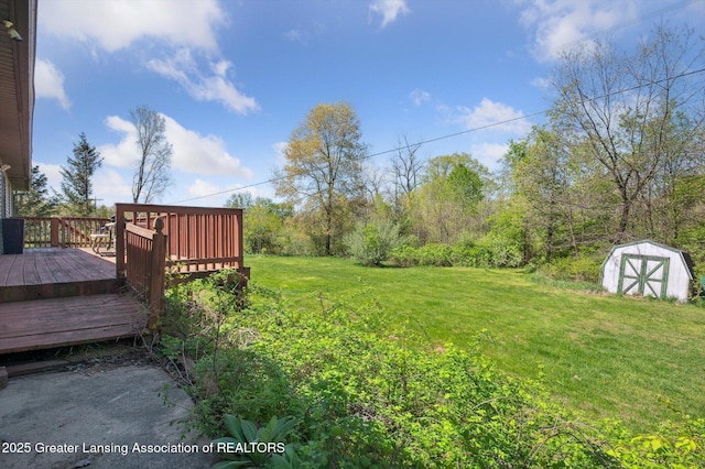 view of grassy yard featuring a storage shed, a deck, and an outdoor structure