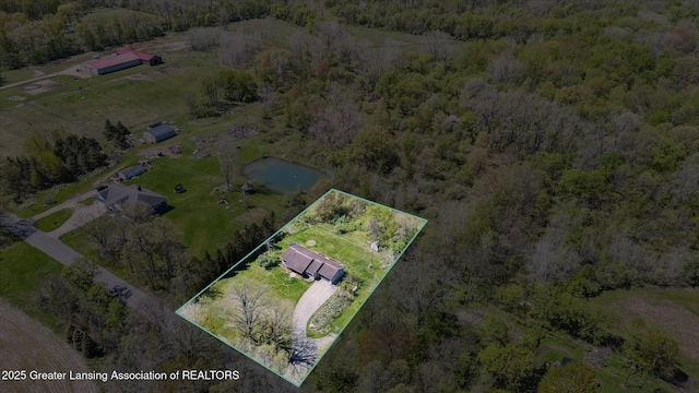 aerial view of property and surrounding area featuring a heavily wooded area and property parcel outlined
