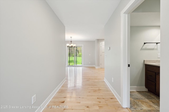 263 E Sherwood Rd, Williamston, MI 48895 - corridor with a chandelier, baseboards, and light wood finished floors