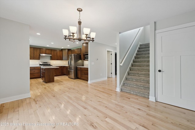 263 E Sherwood Rd, Williamston, MI 48895 - kitchen featuring stainless steel appliances, light wood-type flooring, a chandelier, light countertops, and a kitchen island