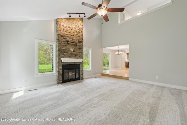 263 E Sherwood Rd, Williamston, MI 48895 - unfurnished living room featuring track lighting, a chandelier, a stone fireplace, a ceiling fan, and high vaulted ceiling