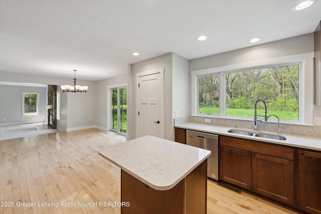 263 E Sherwood Rd, Williamston, MI 48895 - kitchen with a sink, dishwasher, a kitchen island, a chandelier, and light wood finished floors