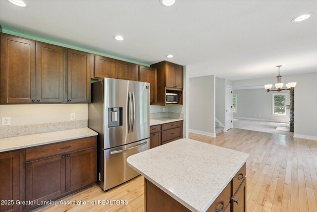 263 E Sherwood Rd, Williamston, MI 48895 - kitchen featuring stainless steel appliances, light countertops, light wood-style flooring, a kitchen island, and a chandelier