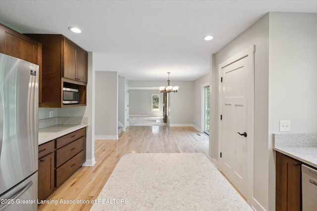 263 E Sherwood Rd, Williamston, MI 48895 - kitchen with appliances with stainless steel finishes, a chandelier, light wood-style floors, light countertops, and baseboards