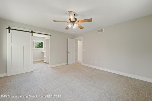 263 E Sherwood Rd, Williamston, MI 48895 - spare room with ceiling fan, light colored carpet, a barn door, and baseboards