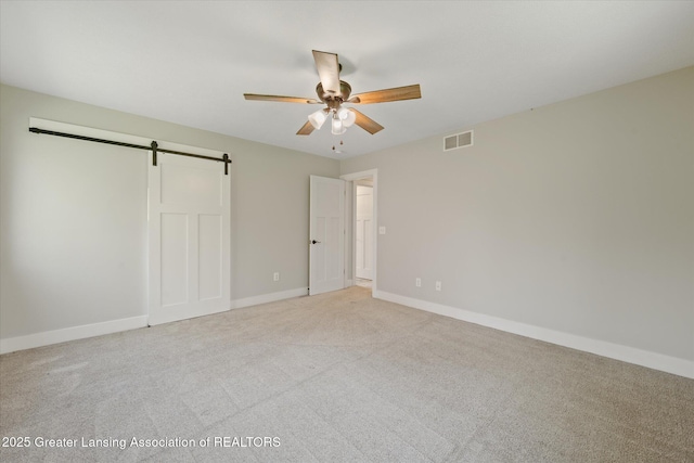 263 E Sherwood Rd, Williamston, MI 48895 - unfurnished bedroom featuring a barn door, light carpet, baseboards, and ceiling fan