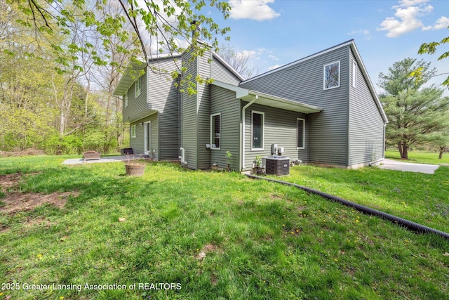 263 E Sherwood Rd, Williamston, MI 48895 - view of property exterior featuring central air condition unit, a lawn, a chimney, and an outdoor fire pit