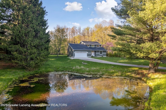 263 E Sherwood Rd, Williamston, MI 48895 - back of house with a lawn, driveway, an attached garage, and a water view