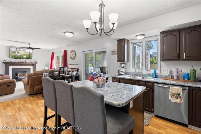 kitchen featuring stainless steel dishwasher, a sink, dark brown cabinetry, and a textured ceiling