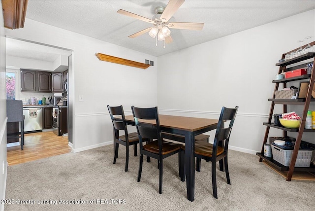 dining area with light carpet, ceiling fan, a textured ceiling, and baseboards