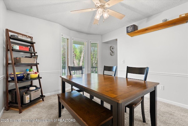 dining room with light carpet, a textured ceiling, a desk, a ceiling fan, and baseboards