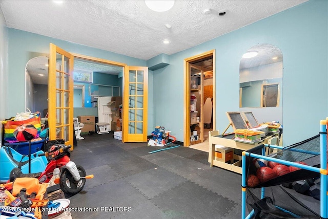 exercise room featuring french doors and a textured ceiling