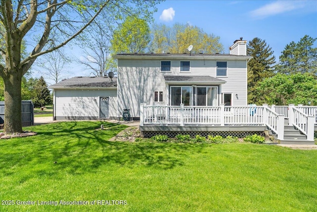 rear view of house featuring a wooden deck, a chimney, a yard, and a sunroom