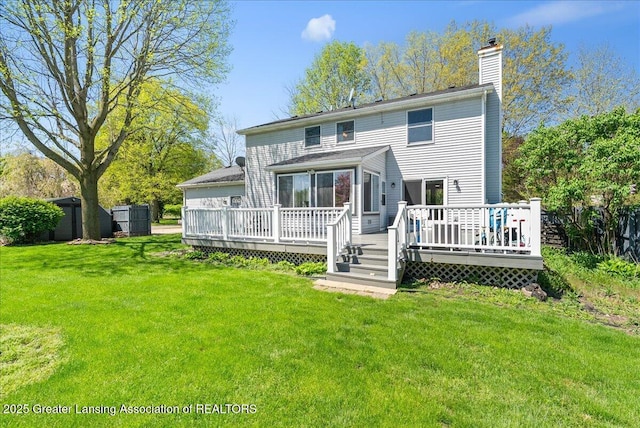 back of property featuring a chimney, a lawn, a deck, and a storage shed