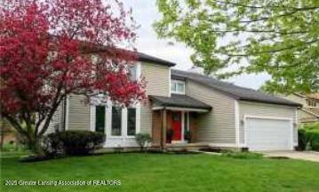 traditional-style home with a garage, driveway, and a front lawn