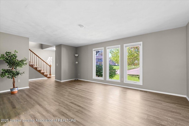 1263 Leeward Dr, Okemos, MI 48864 - unfurnished living room featuring wood finished floors, baseboards, and stairway