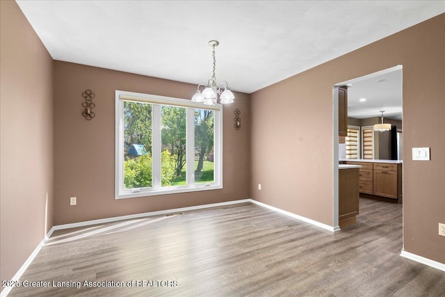 1263 Leeward Dr, Okemos, MI 48864 - unfurnished dining area with a chandelier, wood finished floors, and baseboards
