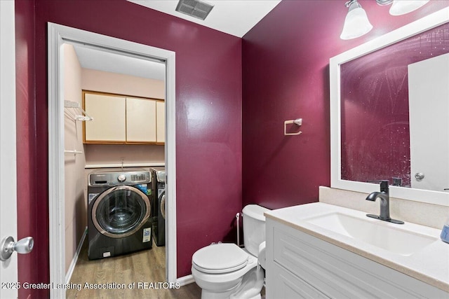 1263 Leeward Dr, Okemos, MI 48864 - bathroom with washing machine and clothes dryer, wood finished floors, toilet, vanity, and baseboards
