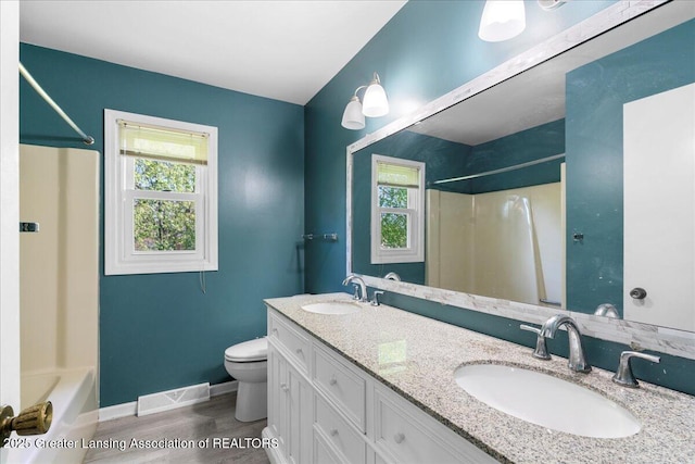 1263 Leeward Dr, Okemos, MI 48864 - bathroom featuring toilet, baseboards, wood finished floors, tub / shower combination, and double vanity