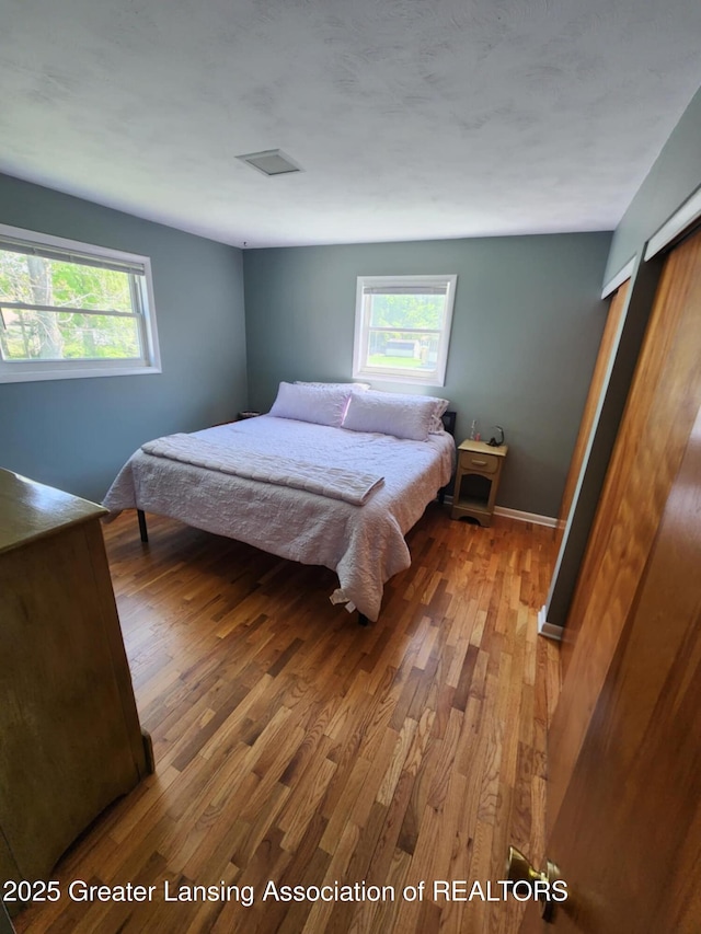 1048 Chris J Dr, Lansing, MI 48917 - bedroom featuring multiple windows and wood finished floors