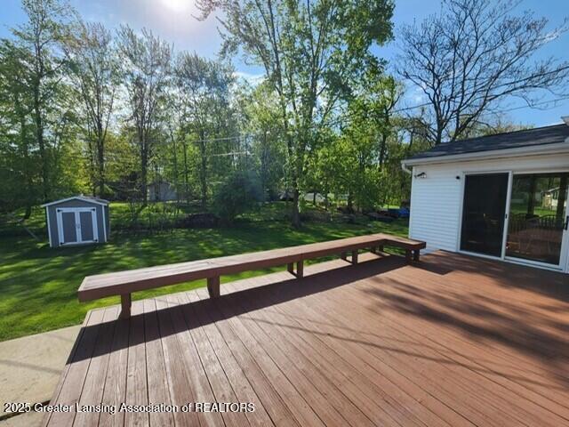1048 Chris J Dr, Lansing, MI 48917 - wooden terrace featuring a lawn, a storage shed, and an outdoor structure