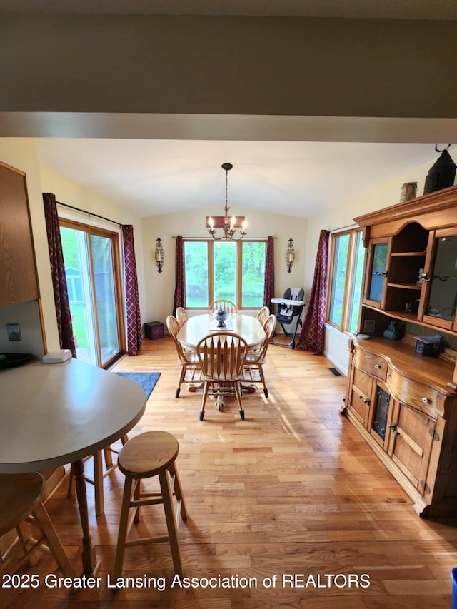 1048 Chris J Dr, Lansing, MI 48917 - dining area with vaulted ceiling, a chandelier, and light wood-style flooring