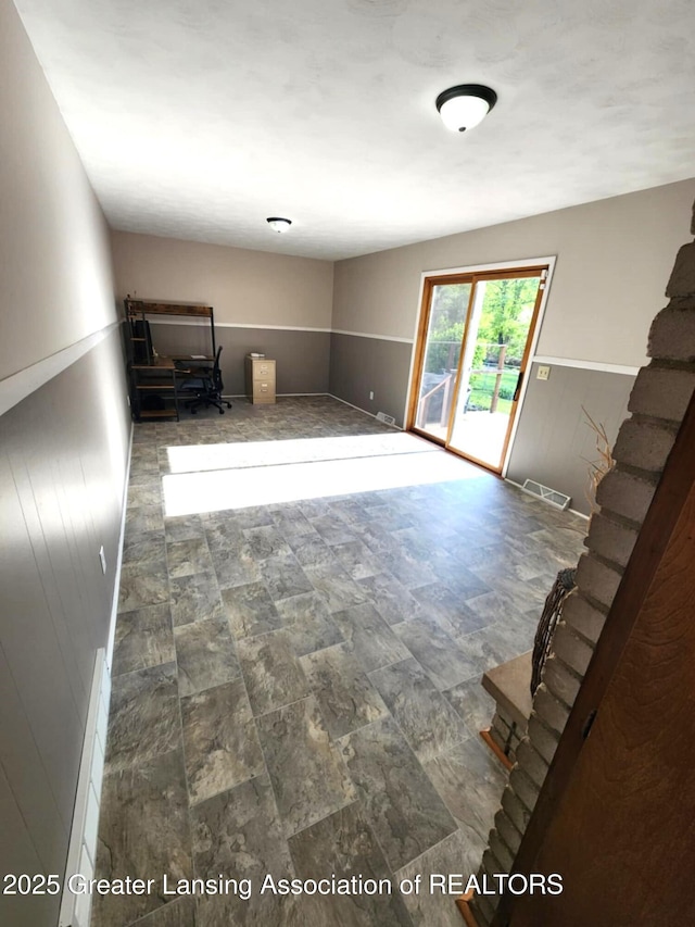 1048 Chris J Dr, Lansing, MI 48917 - unfurnished living room featuring wainscoting, stone finish flooring, and wooden walls