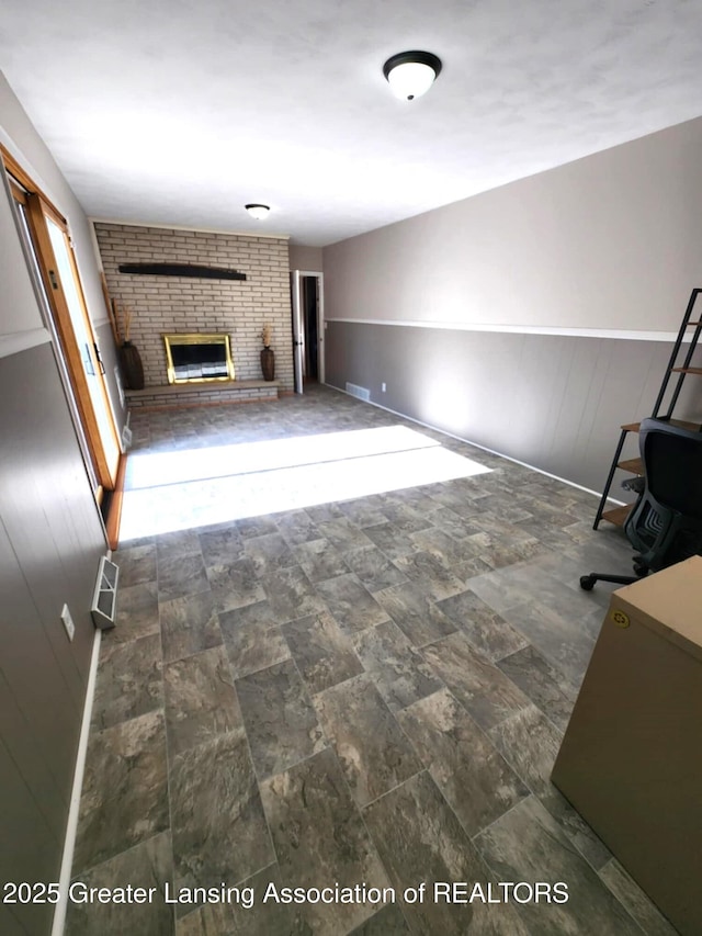 1048 Chris J Dr, Lansing, MI 48917 - unfurnished living room featuring a brick fireplace, stone finish floors, and baseboards