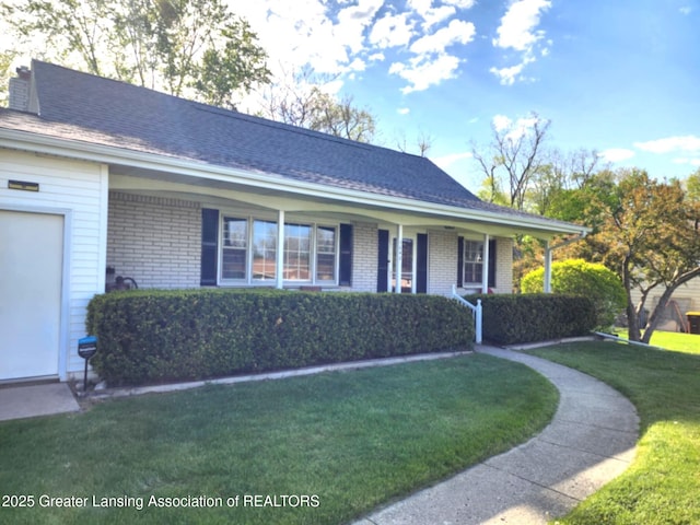 1048 Chris J Dr, Lansing, MI 48917 - single story home featuring brick siding, a front yard, covered porch, and an attached garage