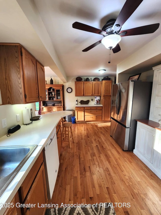 1048 Chris J Dr, Lansing, MI 48917 - kitchen with freestanding refrigerator, brown cabinets, a ceiling fan, and white dishwasher