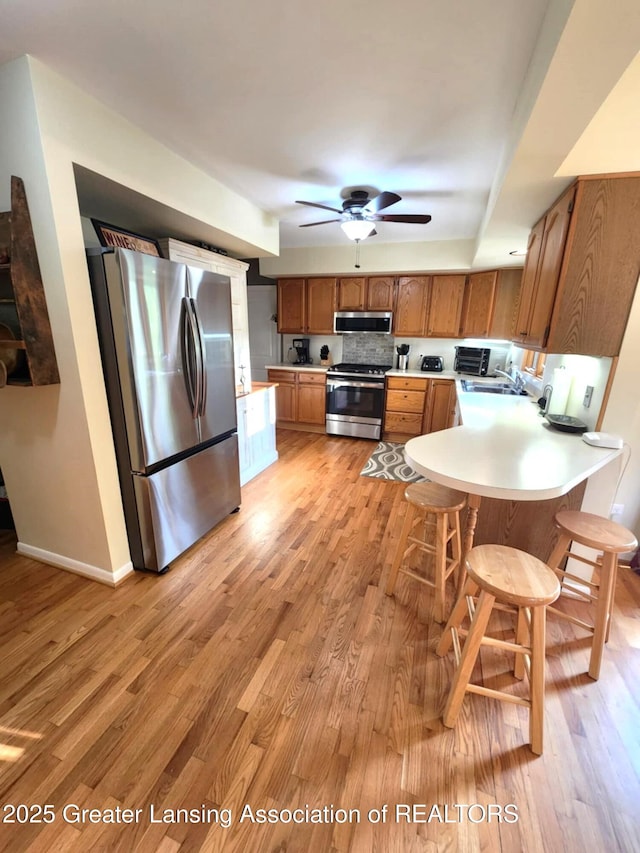 1048 Chris J Dr, Lansing, MI 48917 - kitchen with stainless steel appliances, light countertops, a ceiling fan, and a peninsula
