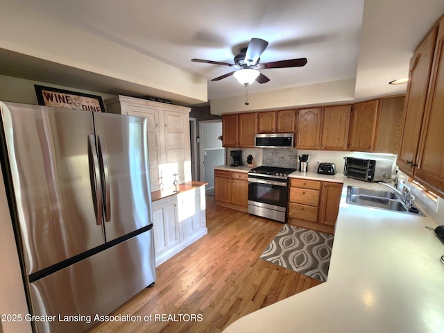 1048 Chris J Dr, Lansing, MI 48917 - kitchen featuring stainless steel appliances, a sink, ceiling fan, backsplash, and light countertops
